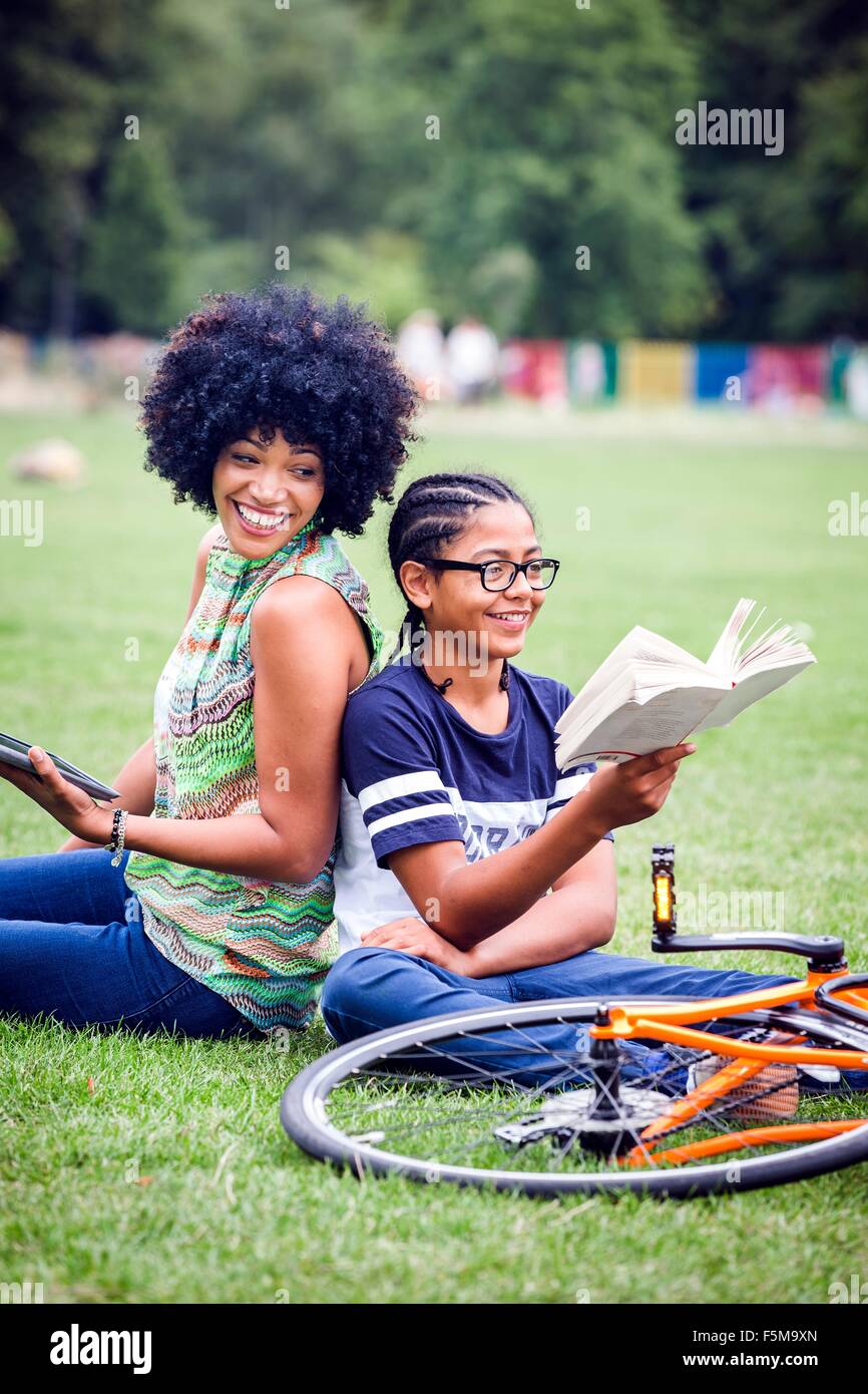 Ragazzo e madre di schiena nella lettura del parco prenota Foto Stock