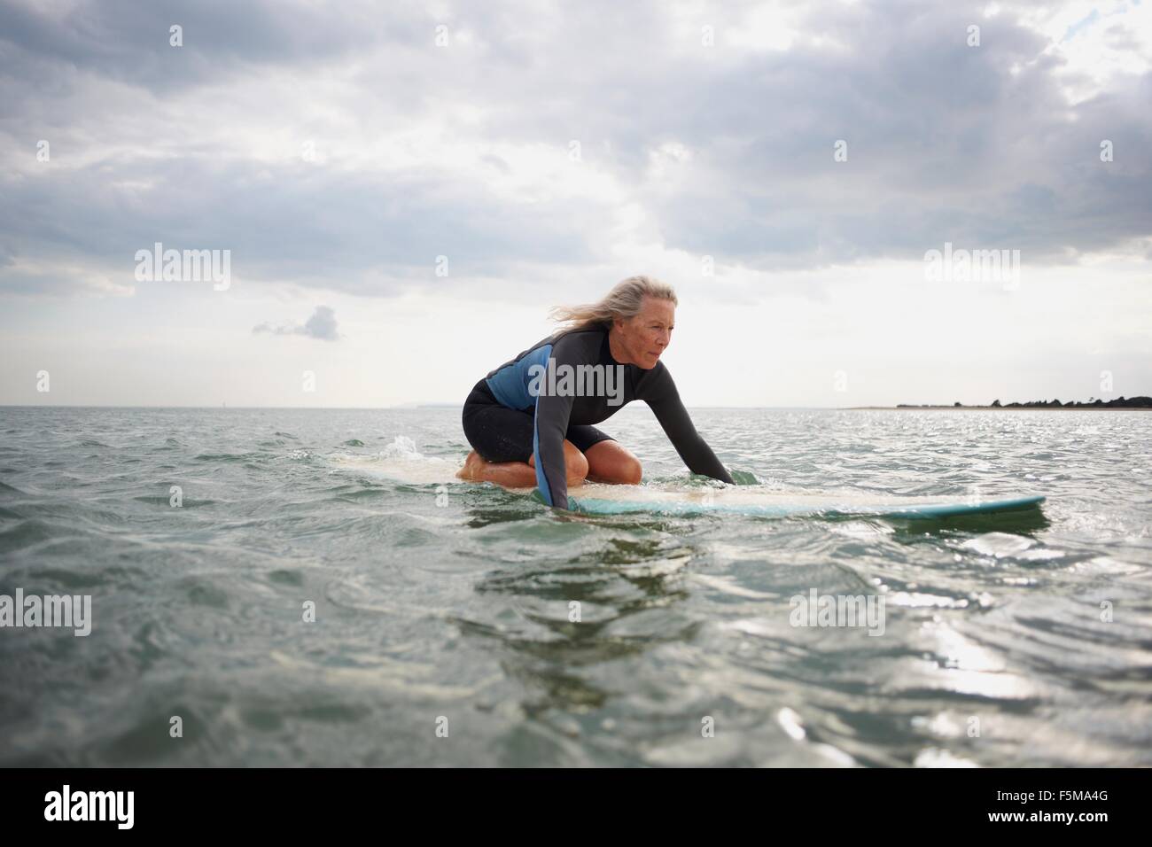 Senior donna sulla tavola da surf in mare, paddleboarding Foto Stock