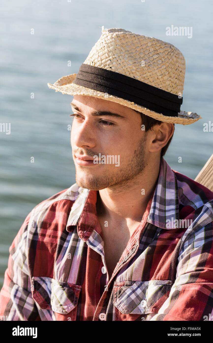 Ritratto di giovane uomo che indossa cappello di paglia che guarda lontano Foto Stock