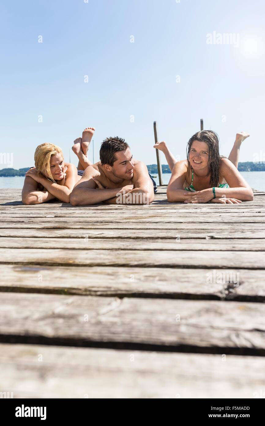 La superficie di visualizzazione a livello di amici che giace sulla parte anteriore sul molo di legno a prendere il sole, Schondorf, Ammersee, Baviera, Germania Foto Stock