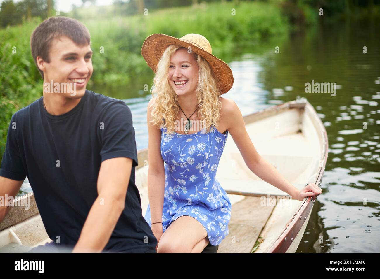 Coppia giovane in barca a remi sul fiume rurale Foto Stock