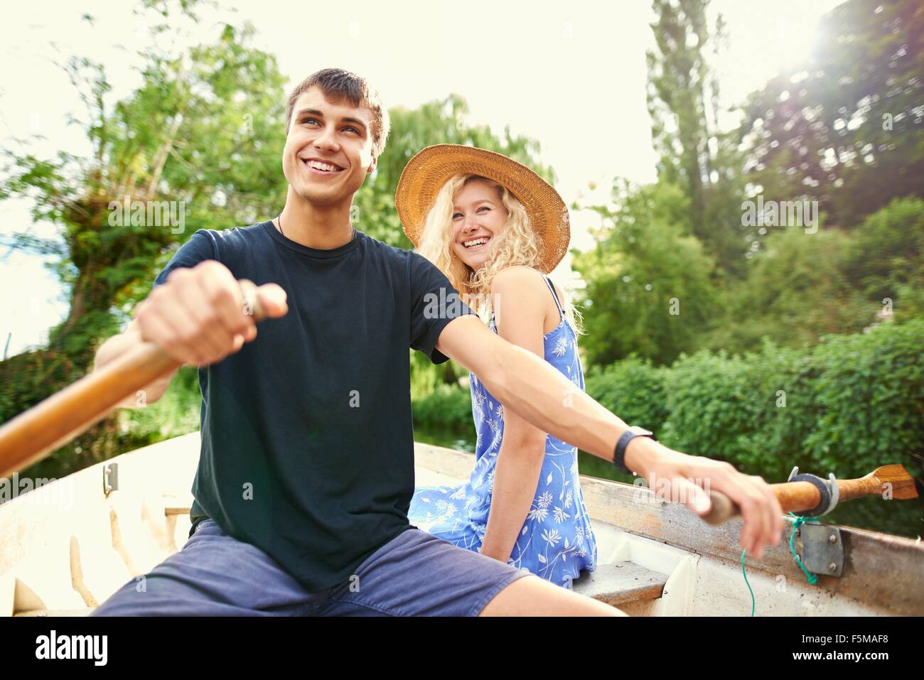 Coppia giovane barca a remi sul fiume rurale Foto Stock