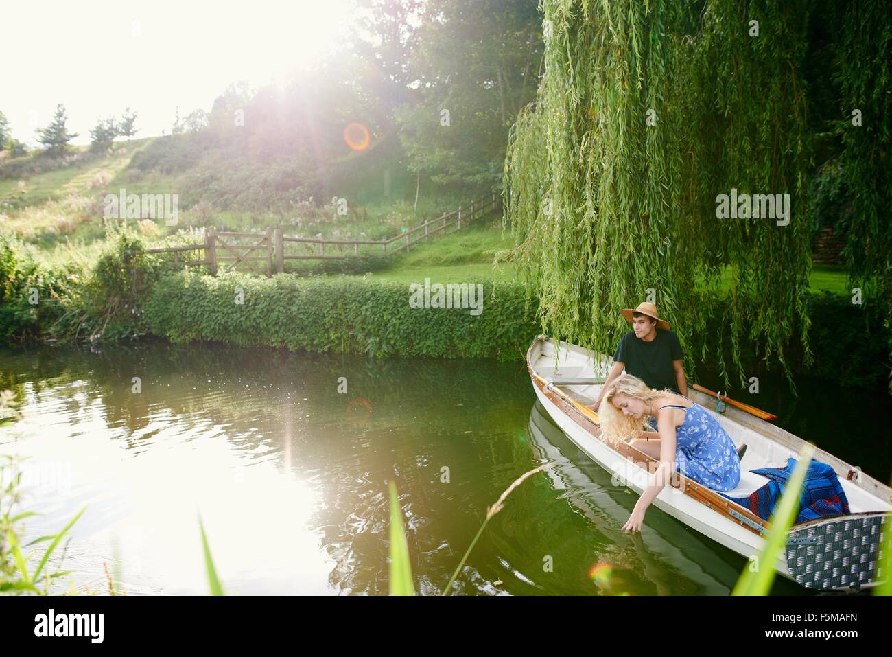 Giovane donna con il fidanzato di toccare l'acqua dal fiume in barca a remi Foto Stock
