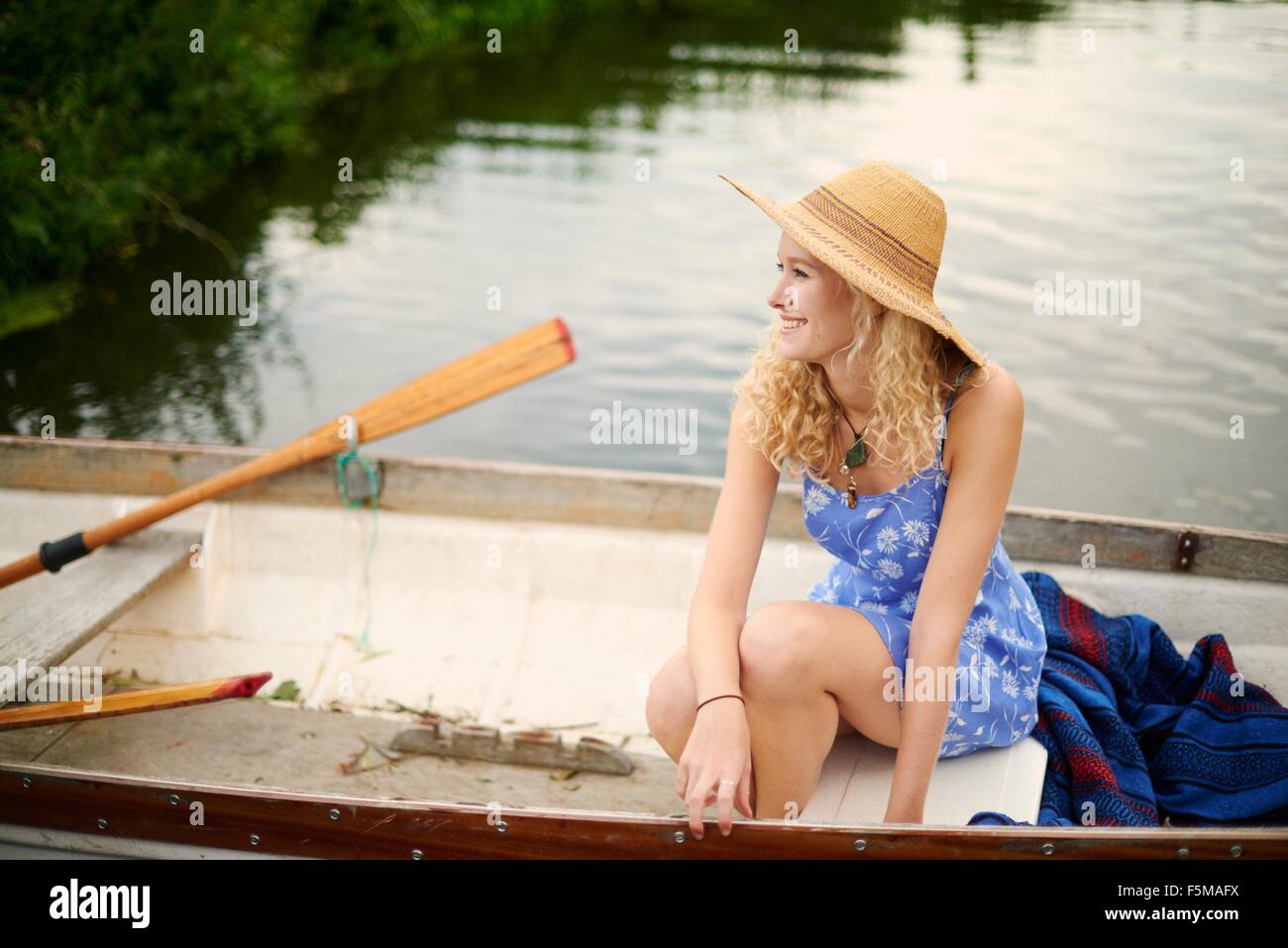 Ritratto di giovane donna con capelli lunghi biondi in barca a remi sul fiume Foto Stock