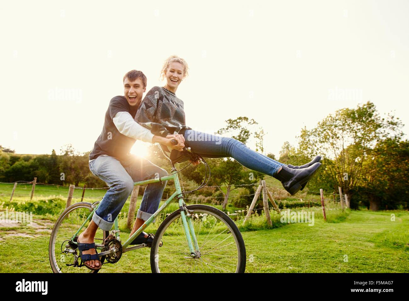 Giovane donna seduta su fidanzati manubrio di bicicletta Foto Stock