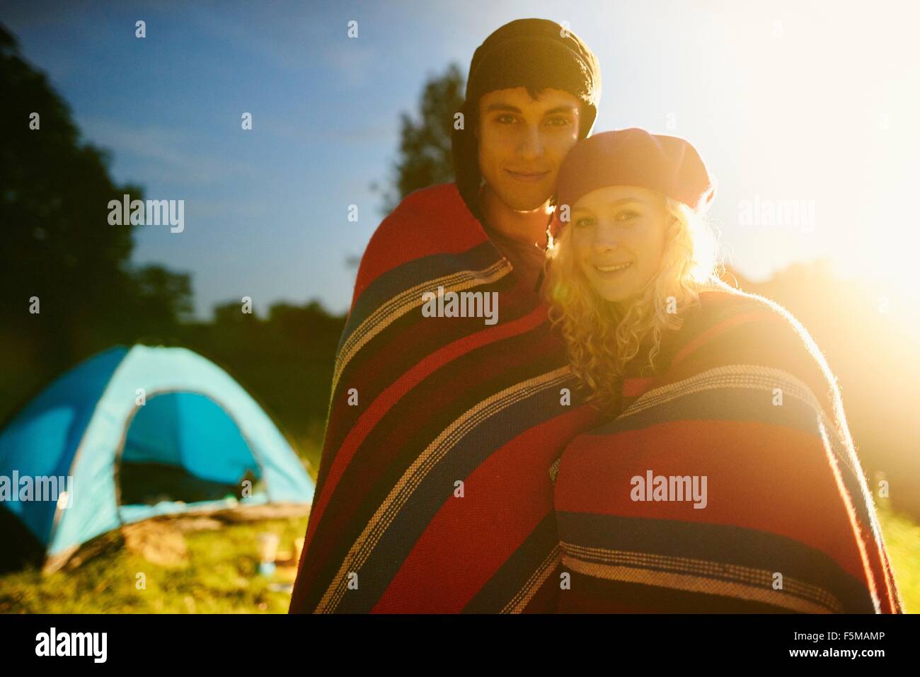 Ritratto di giovane romantico camping giovane avvolto in una coperta al tramonto Foto Stock