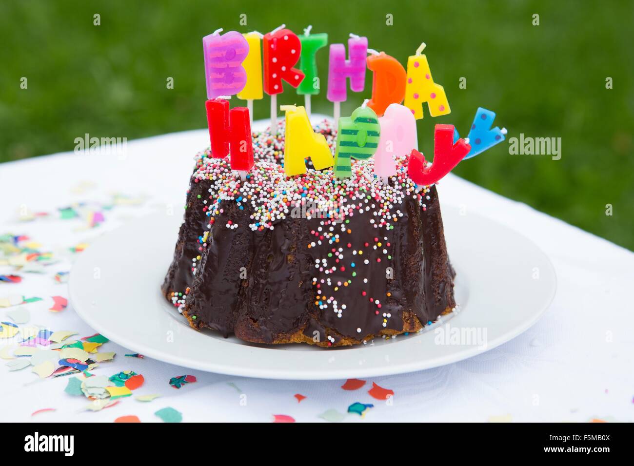 Torta di compleanno con candele sul tavolo da giardino Foto Stock