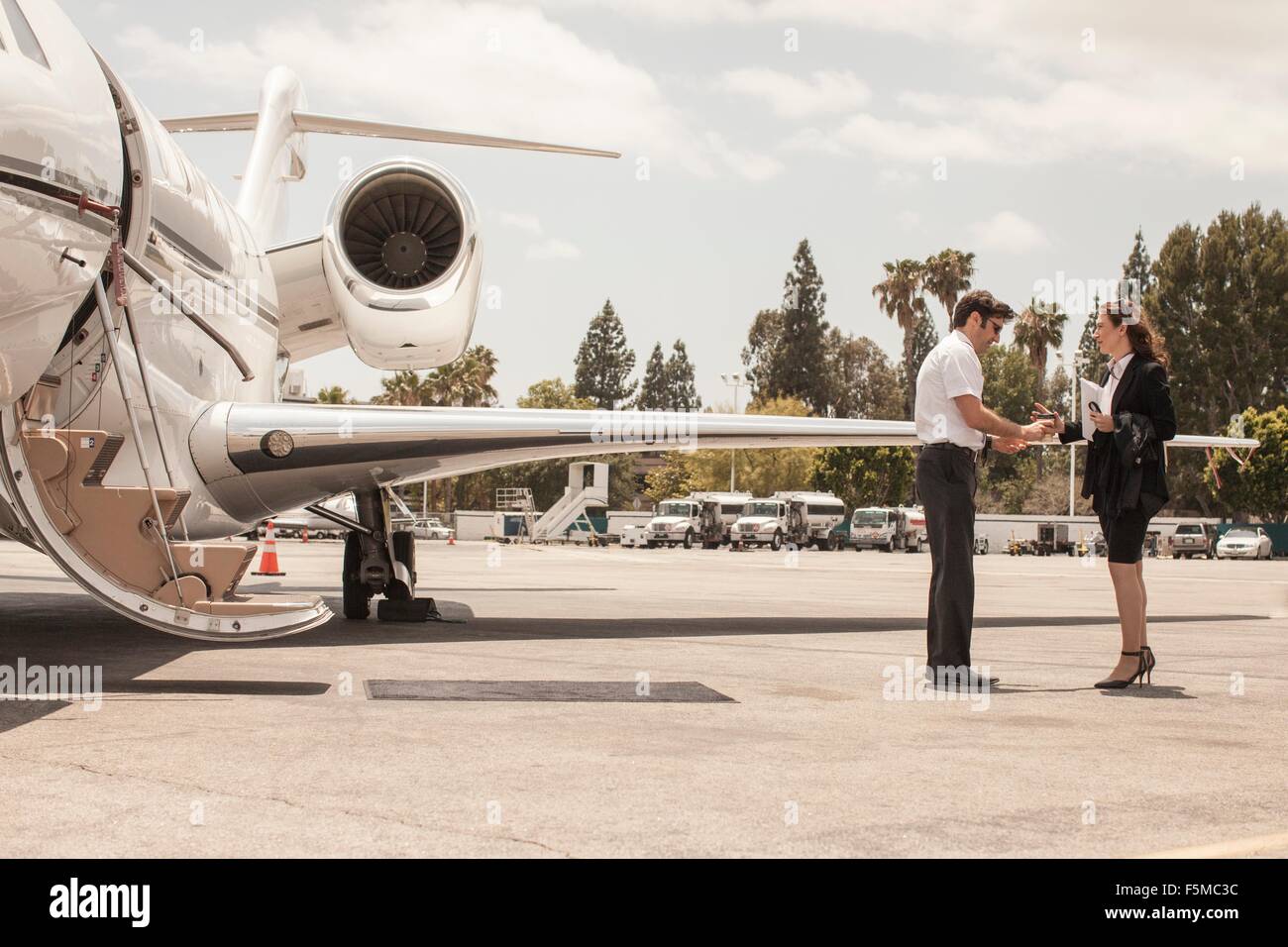 Imprenditrice femmina stringono le mani con jet privato pilota su airport Foto Stock