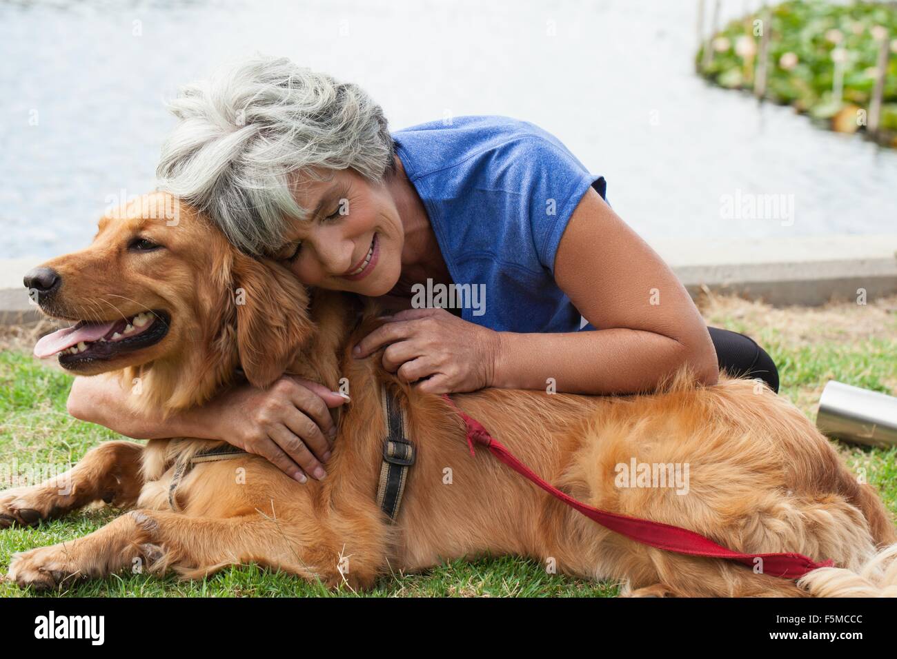 Donna matura abbracciando cane, all'aperto Foto Stock
