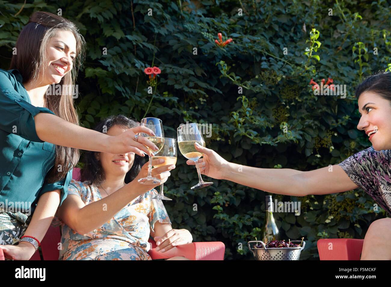 Tre donne la tostatura con vino bianco sul patio Foto Stock