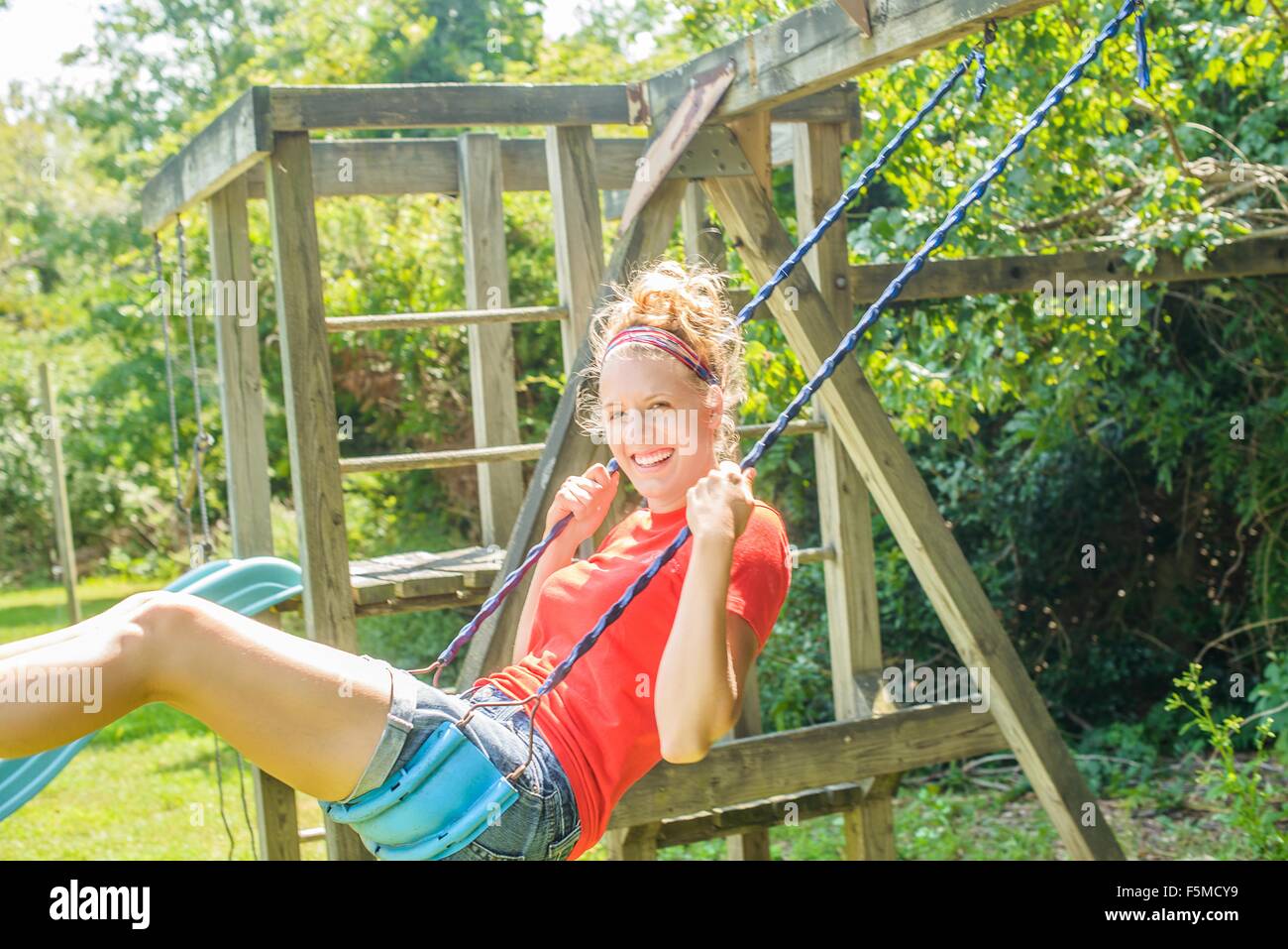 Giovane donna cantare su giardino swing Foto Stock