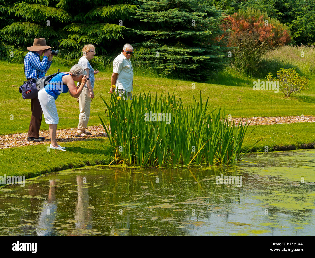 Turisti che si godono una passeggiata intorno al lago a Hopton Hall giardino nel Derbyshire Dales Peak District Inghilterra REGNO UNITO Foto Stock