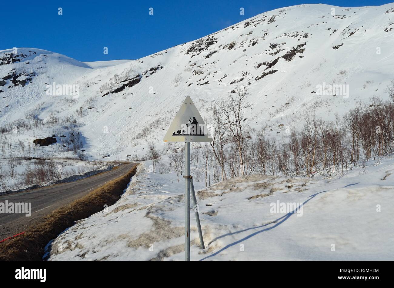 La caduta di roccia segno di pericolo di fronte a una coperta di neve montagna sulla sommità del Kaperdalen, Norvegia Foto Stock