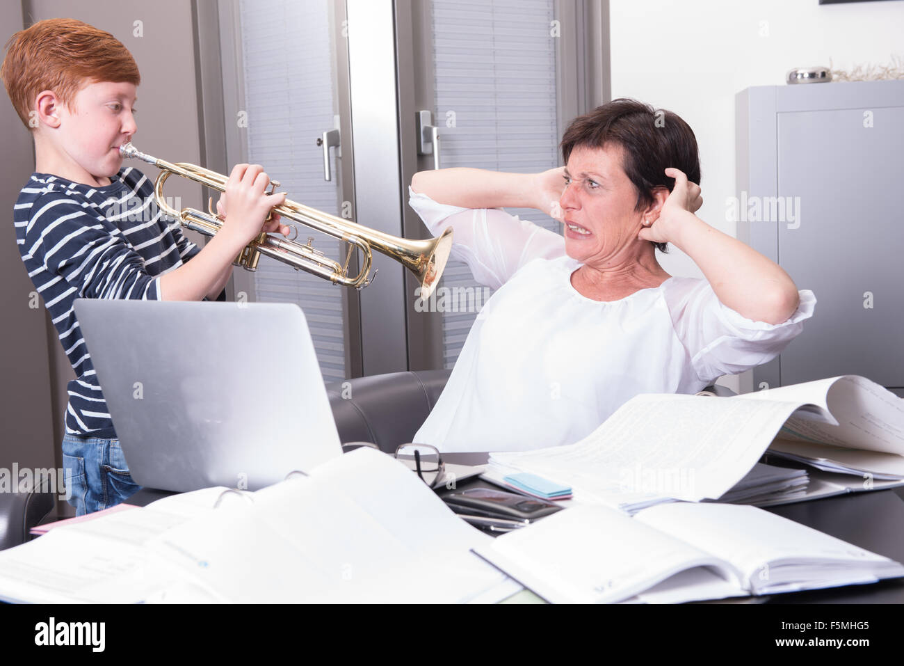 La madre lavora in un home office, figlio è inquietante da suonare la tromba Foto Stock