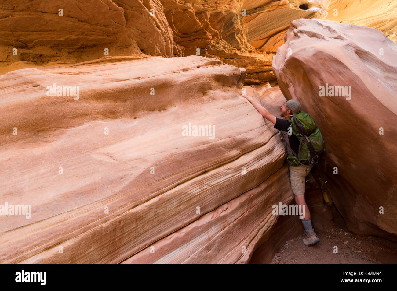 Un escursionista in piedi al di sotto di una cricca eroso al di sopra di uno slot canyon nel canyon Crack, San Rafael Swell, Utah Foto Stock