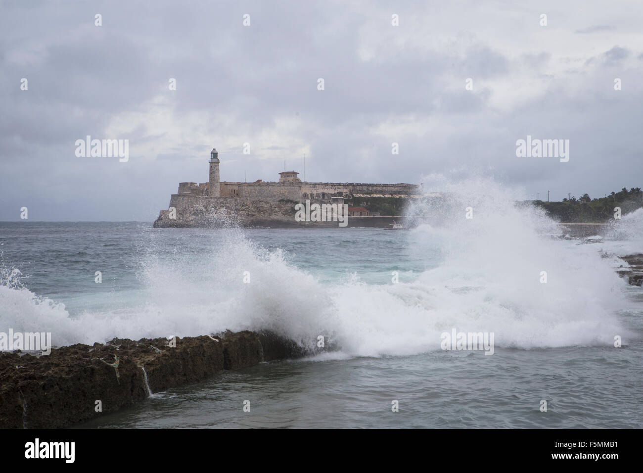 Onde che si infrangono vicino al Malecon con Morro Castle in background, Havana, Cuba Foto Stock