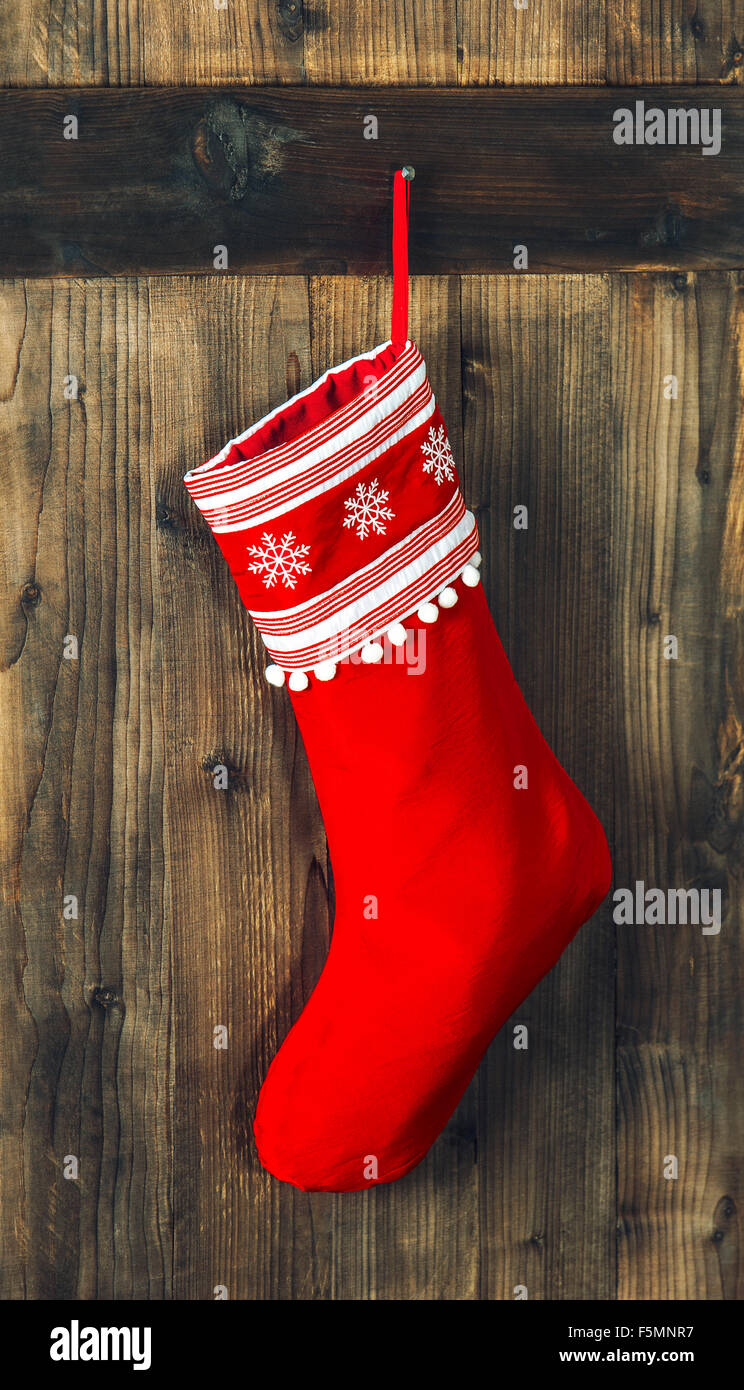Calza di Natale. Red calza appesa sopra in legno rustico sfondo. Vacanze a decorazione Foto Stock
