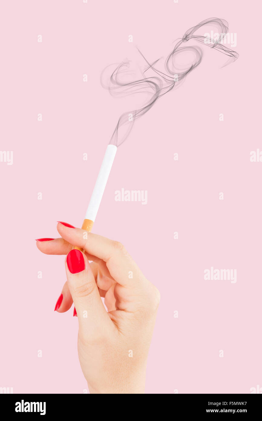 Femmina di mano azienda sigaretta, fumo formante la parola stop isolato su sfondo rosa. Femminile abuso di tabacco. Foto Stock