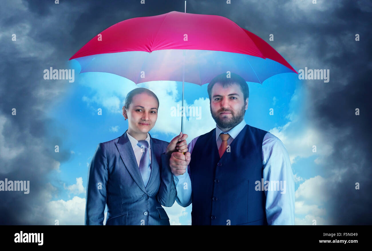 Azienda giovane sotto ombrellone contro il cielo scuro Foto Stock