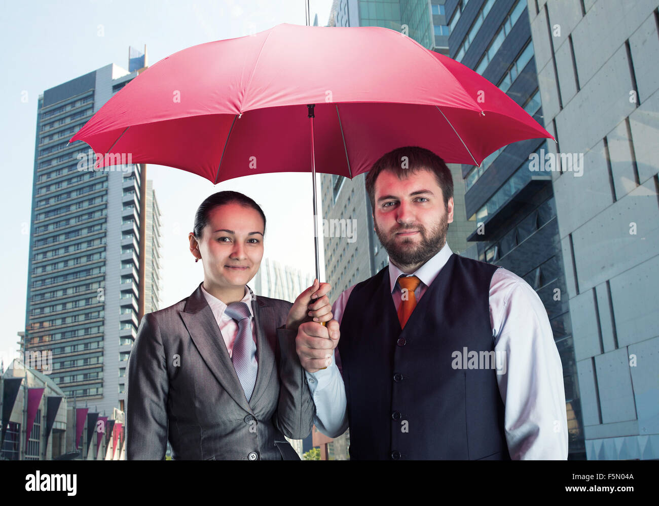 Azienda giovane sotto ombrellone contro la città Foto Stock