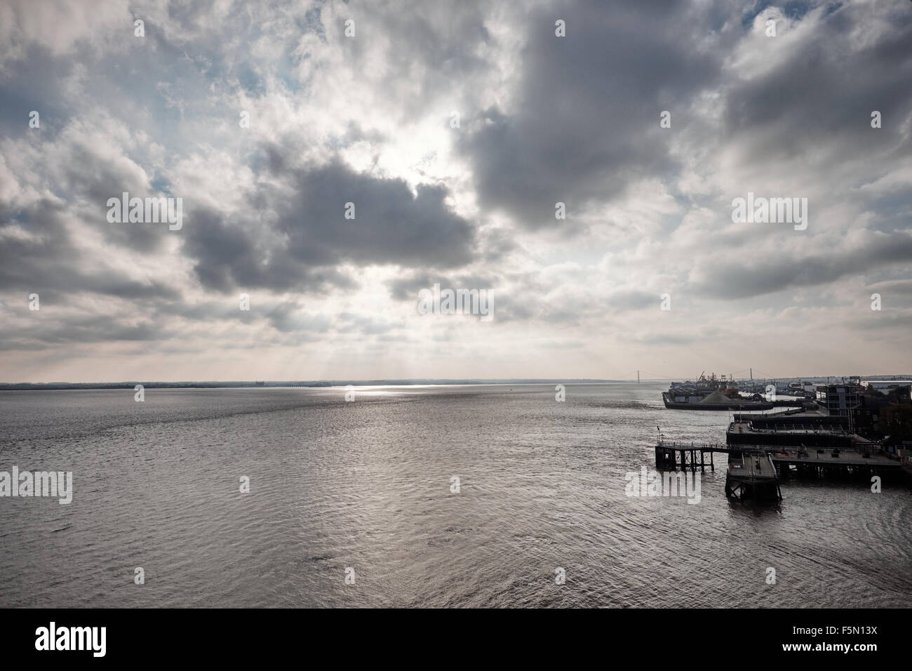Visualizzare il fiume Humber Estuary in Nord Ovest Inghilterra con pontili e il sole che tramonta dietro le nuvole Foto Stock