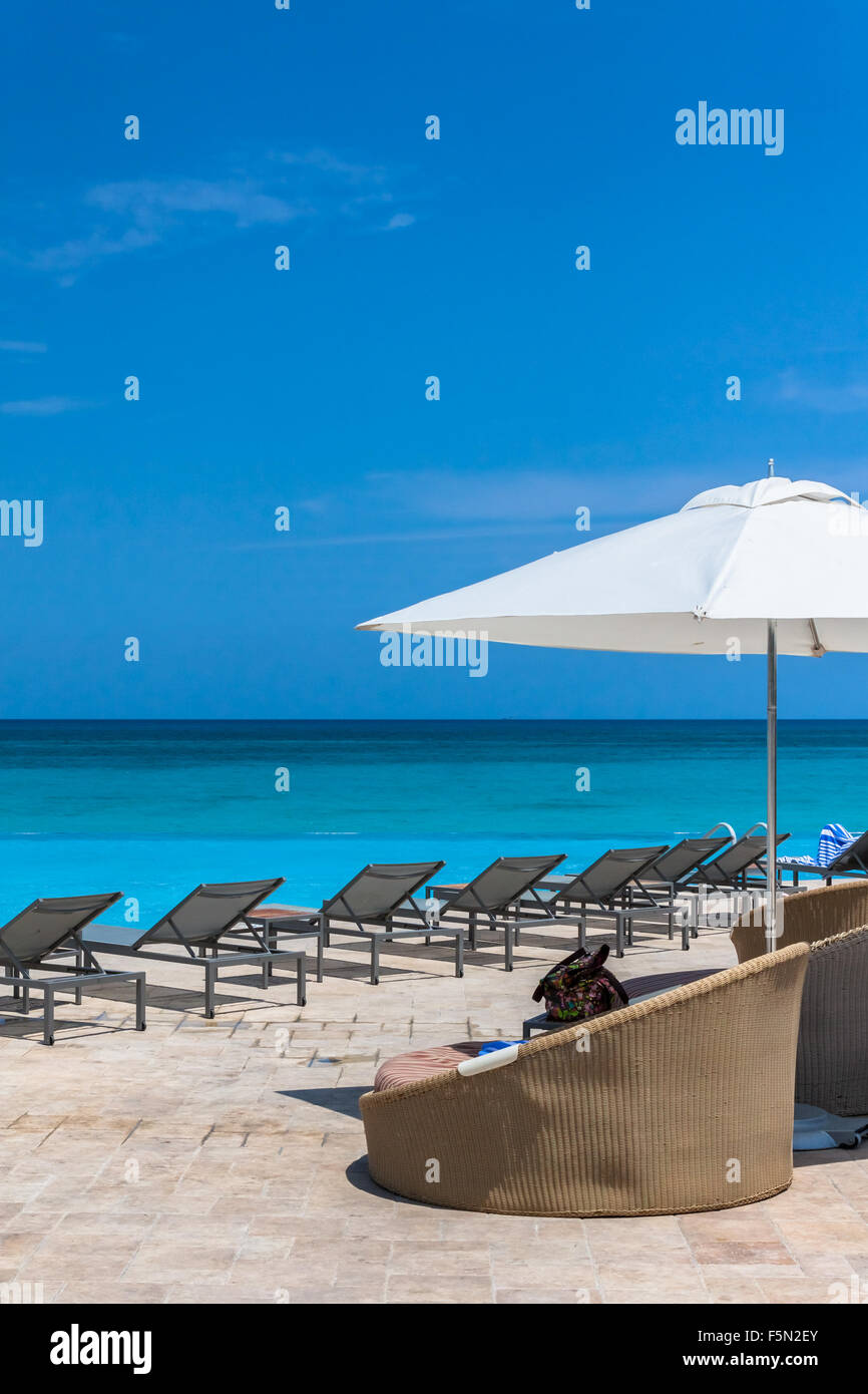 Una grande rotonda Sedia lounge siede sotto un ombrello di grandi dimensioni con una bella pacifica cielo blu vista oceano. Foto Stock