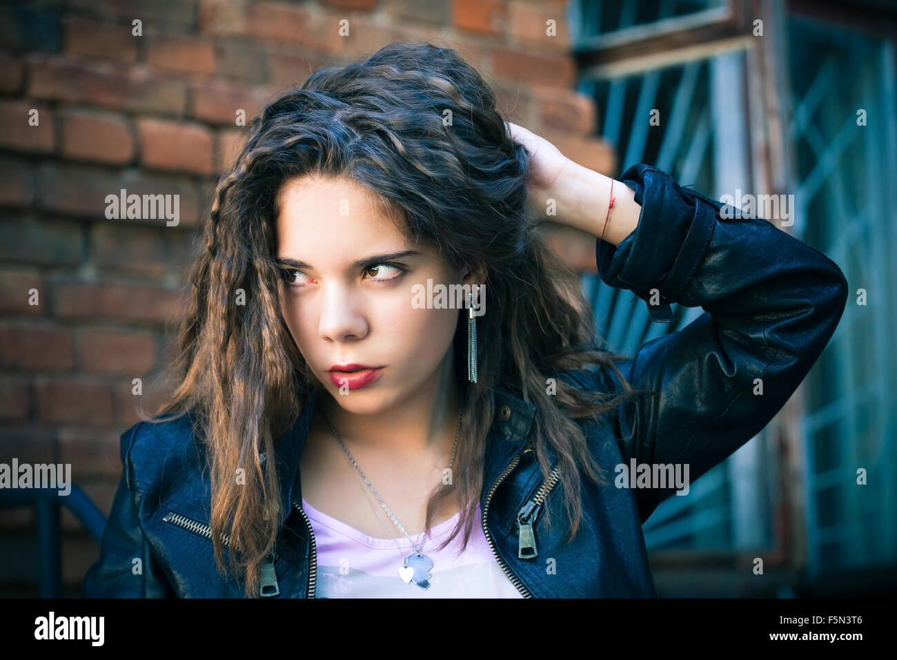 Giovane donna in giacca di pelle su uno sfondo di un vecchio muro Foto Stock