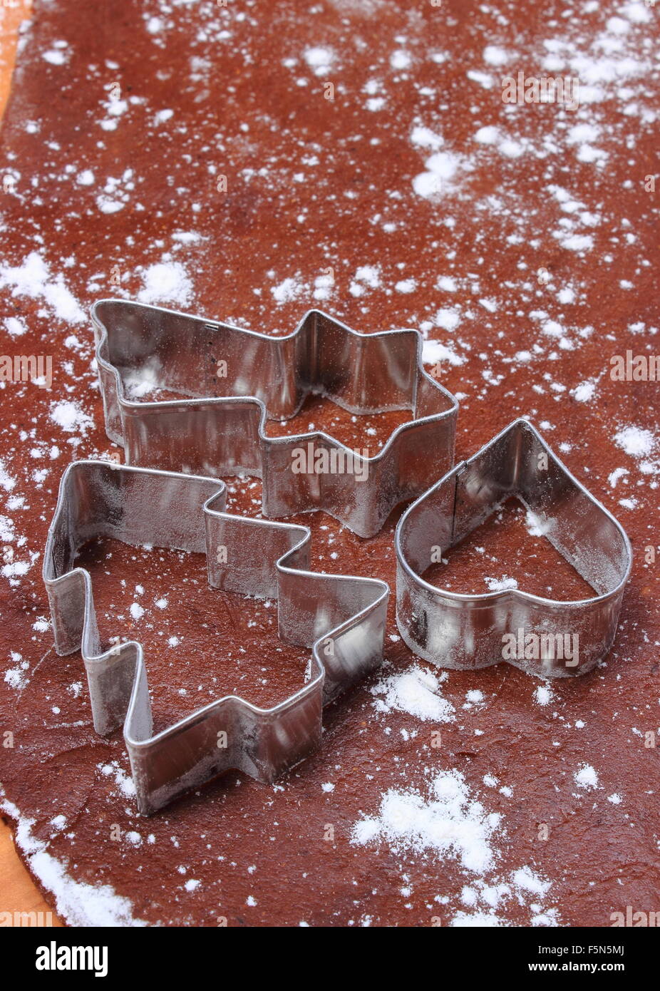 Cookie cutters in forma di albero di natale e di cuore giacente su impasto per pan di zenzero, concetto di cottura e il tempo di Natale Foto Stock