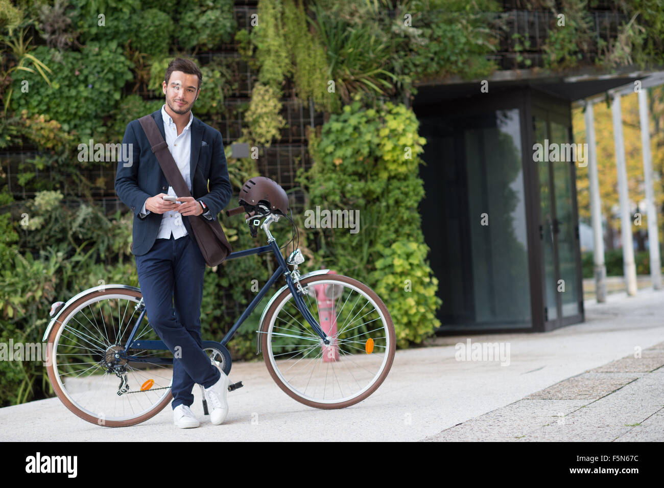 Imprenditore parlando al cellulare seduti sulla sua bicicletta in città Foto Stock