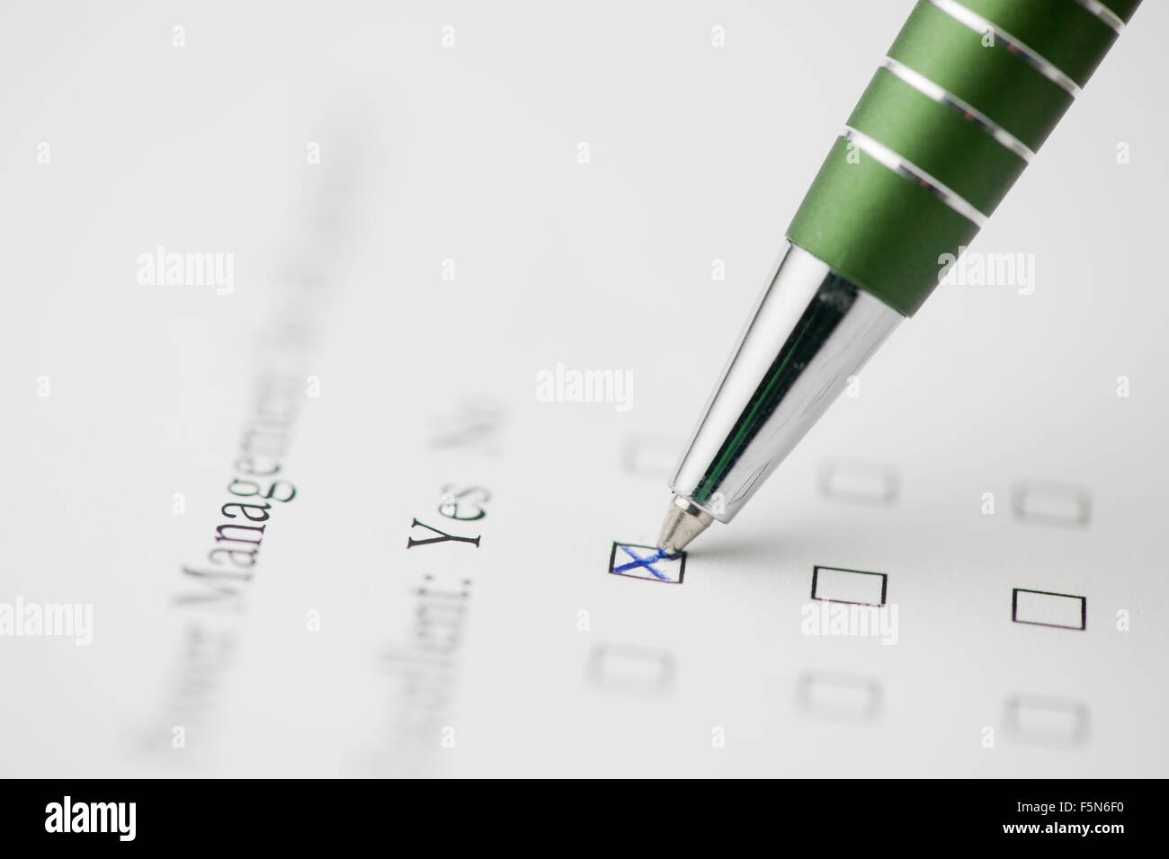 Close-up di una penna verde un modulo su incrocio con scrittura in inglese " SÌ " con molto bassa profondità di campo Foto Stock