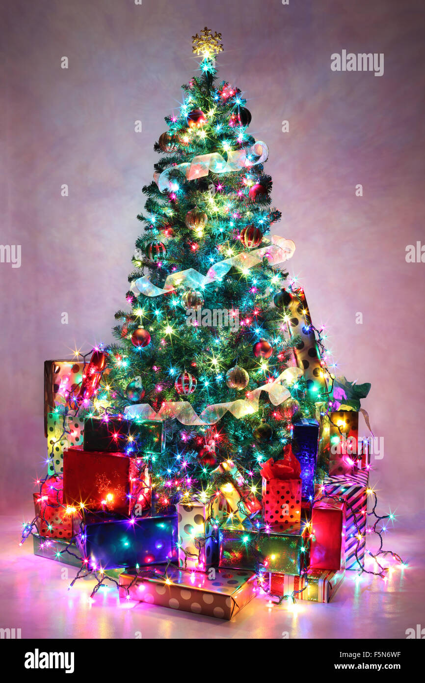 Albero di Natale decorato con luci colorate circondato da presenta Foto  stock - Alamy