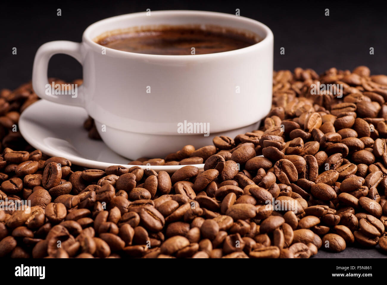 Il caffè in una tazza e un mucchio di chicchi di caffè Foto Stock
