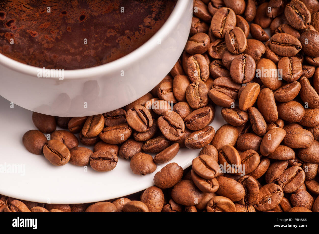 Il caffè in una tazza e un mucchio di CoffeeBeans Foto Stock