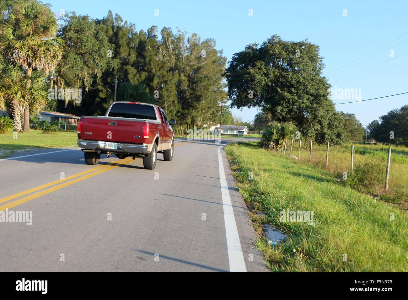 Red carrello il sorpasso su una doppia linea gialla che si avvicinano ad un piegare in strada Foto Stock