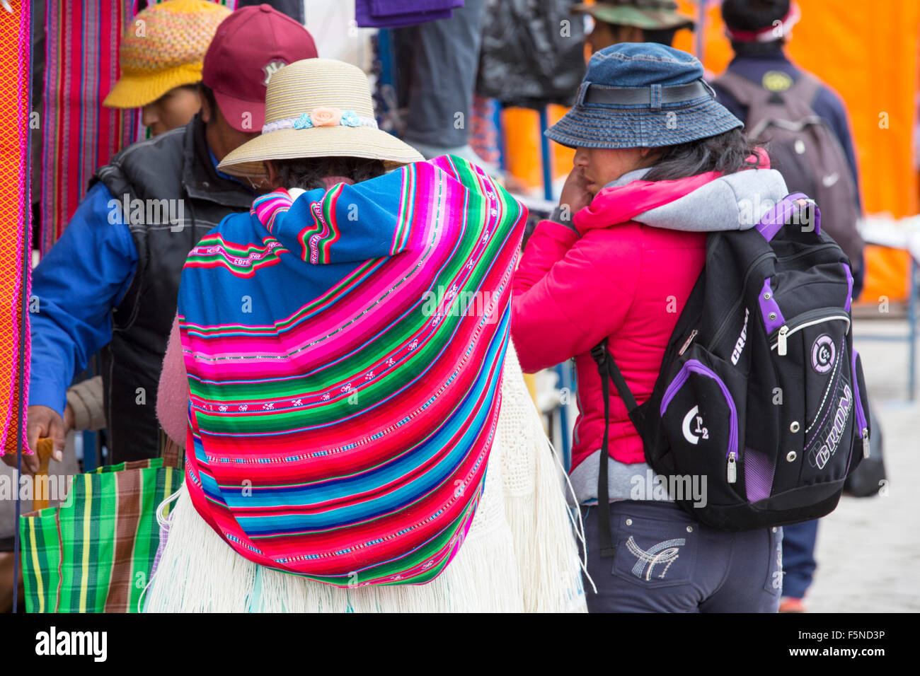 Una donna indigena e il bambino ad una strada del mercato di El Alto, La Paz, Bolivia, Sud America, che mostra il tradizionale e moderna Foto Stock