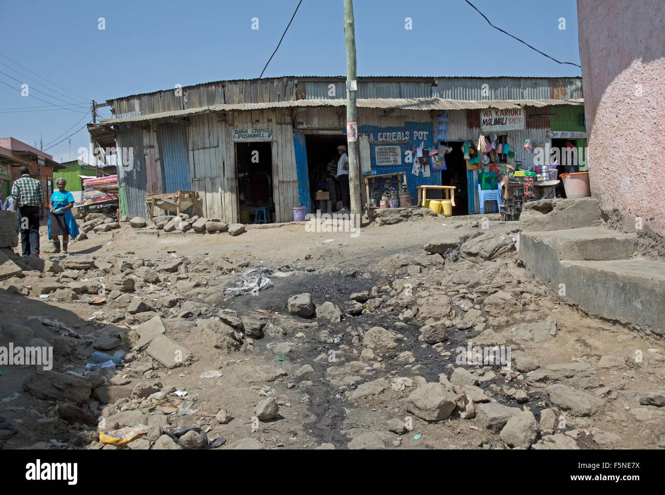 Scena di strada con ferro corrugato negozi e rock e i rifiuti sparsi in strada in African bidonville Kamere Township Naivasha Kenya Foto Stock