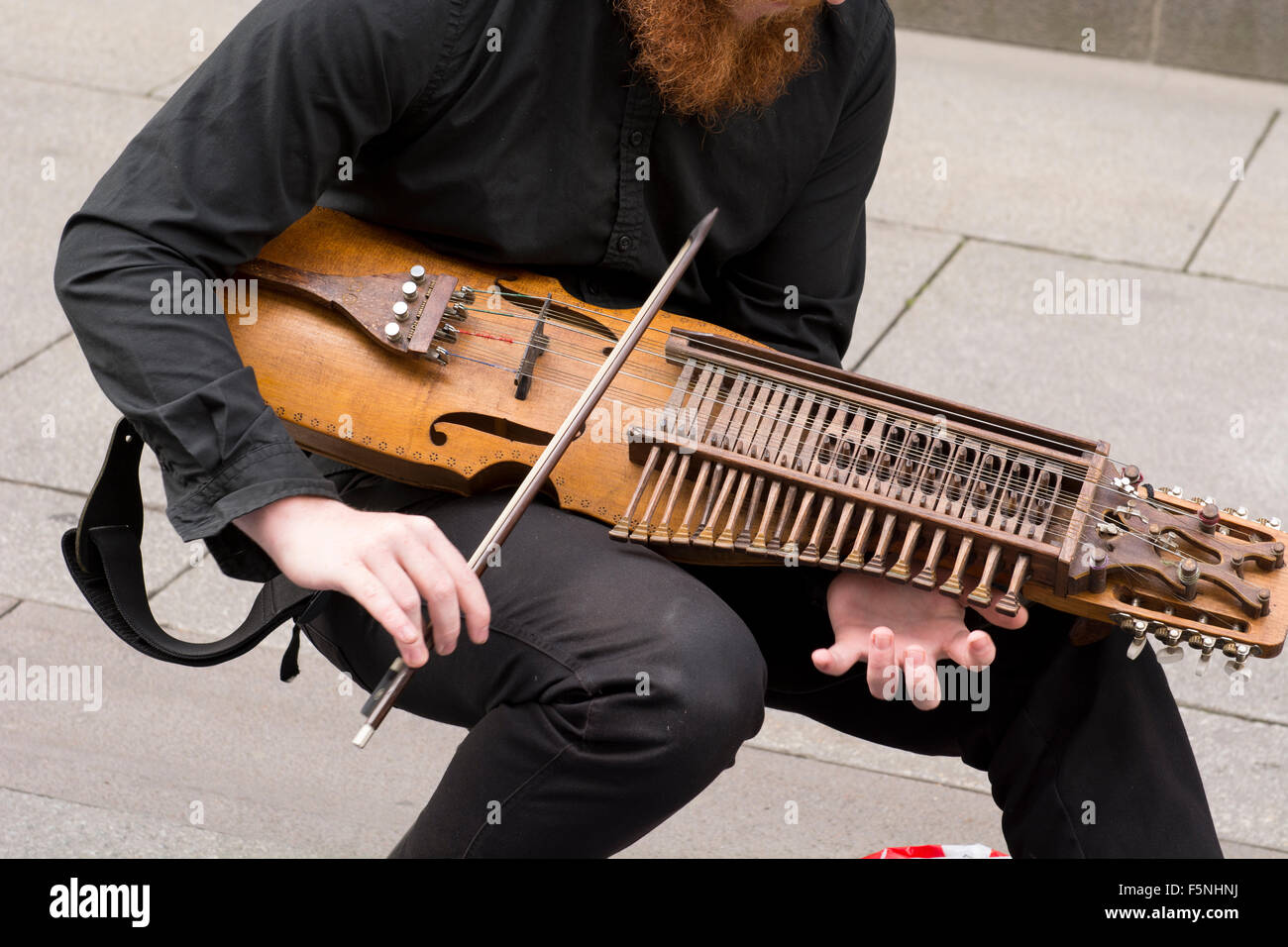 Norvegia, Oslo. Karl Johans Gate, al centro di una strada pedonale. Musicista di strada giocare unico strumento a corda. Foto Stock