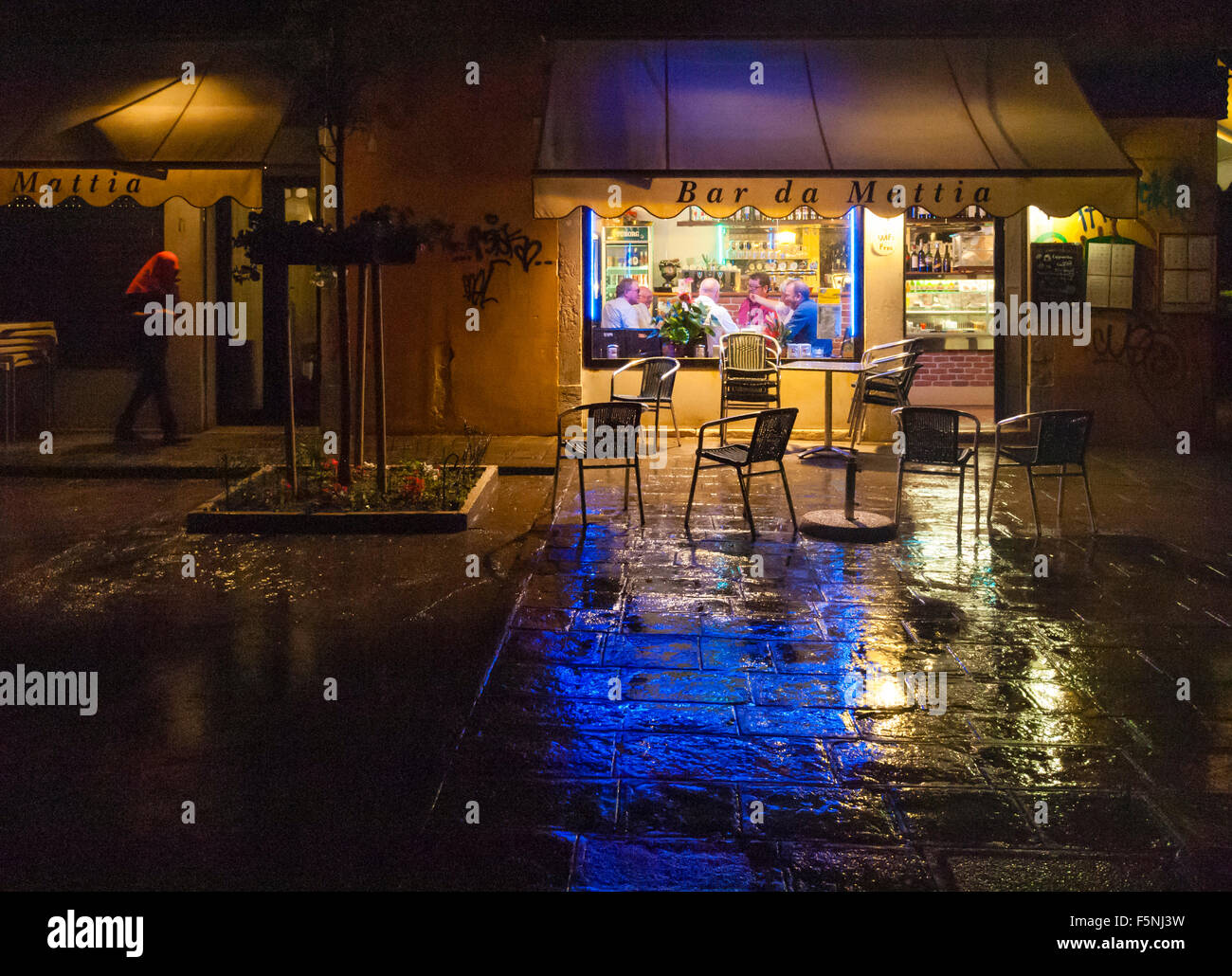 Un gruppo di uomini sono seduti in un piccolo locale bar a Venezia, Italia, durante la serata mentre fuori piove. Foto Stock