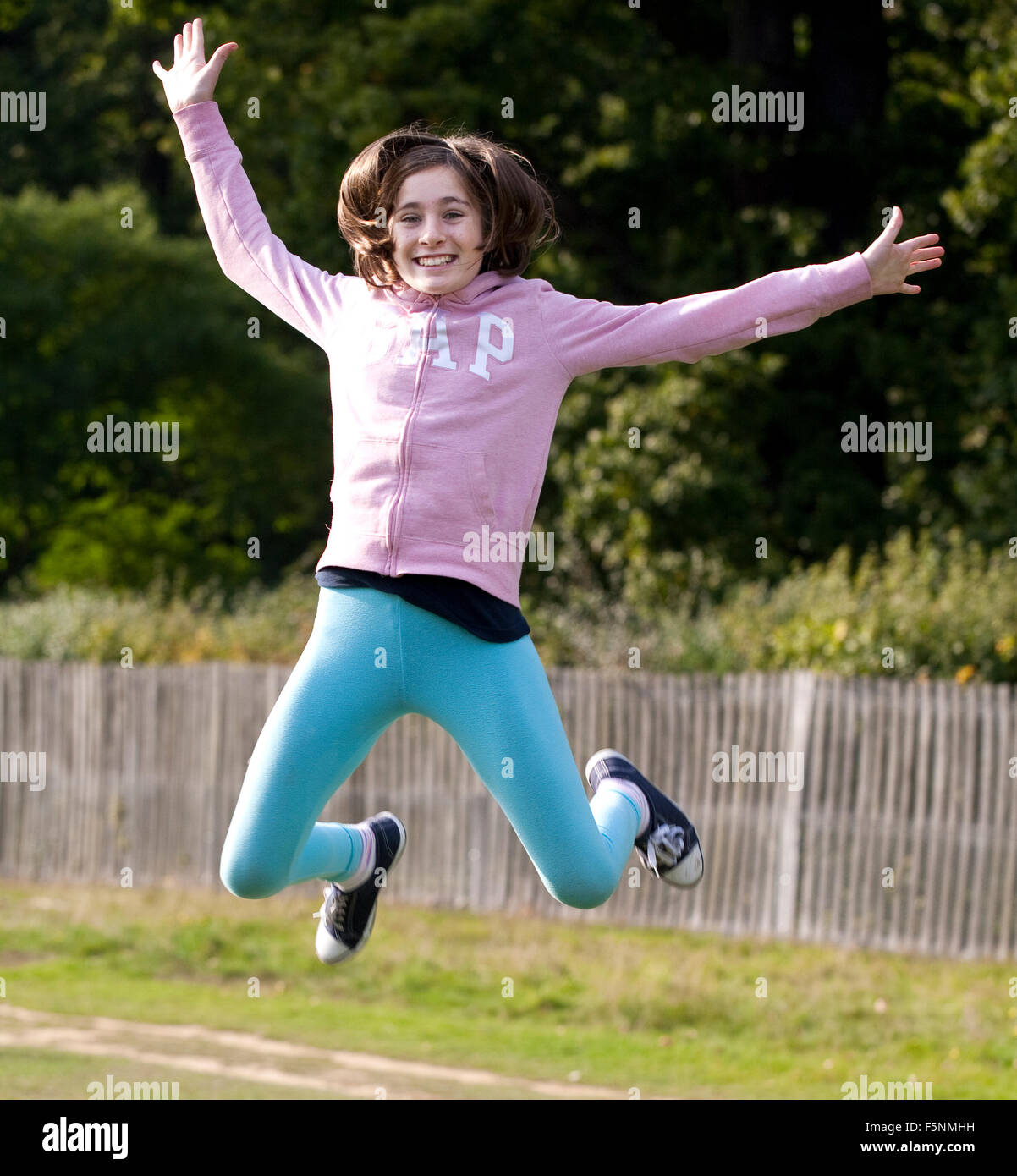 Una ragazzina salta in aria il lancio da un grande log vecchi Foto Stock