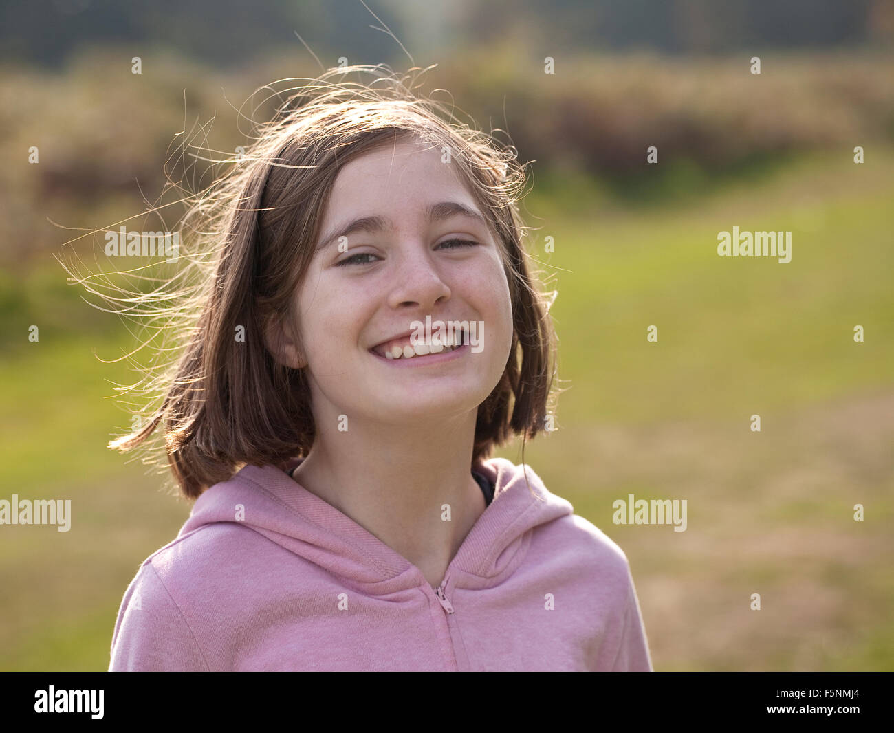 Sono contento. Una giovane ragazza sorridente, undici anni, è retro illuminato dal sole che mostra il suo volare lontano i capelli. Foto Stock