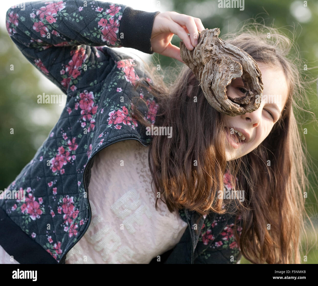 In cerca di mostri. In vena di Spiderwick, questa ragazza è tramite un foro di un pezzo di legno per spiare i mostri. Foto Stock