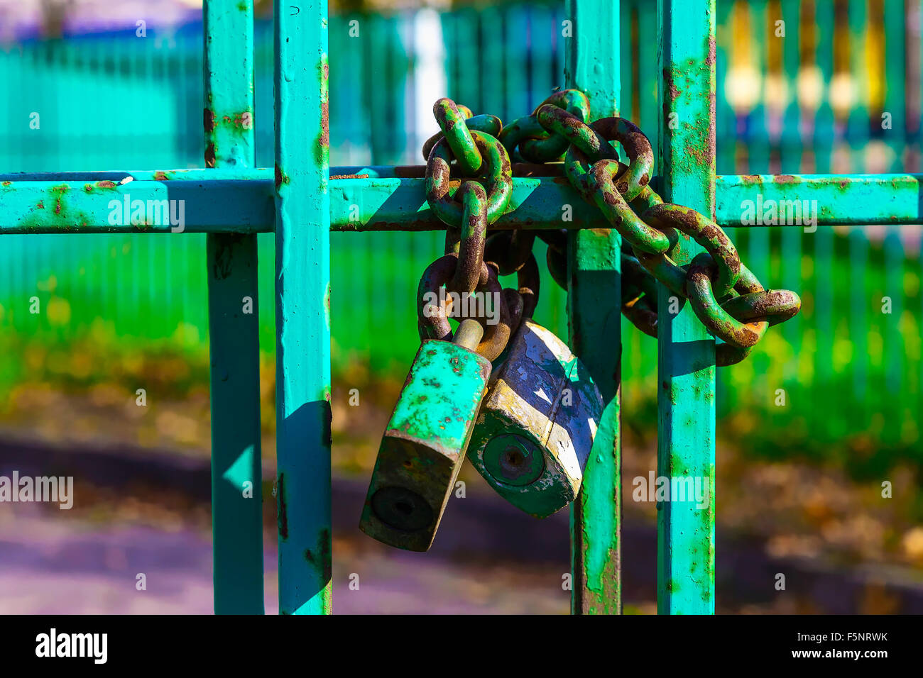 Il focus principale di immagine sulla recinzione metallica con serratura arrugginita e catena su sfondo sfocato Foto Stock