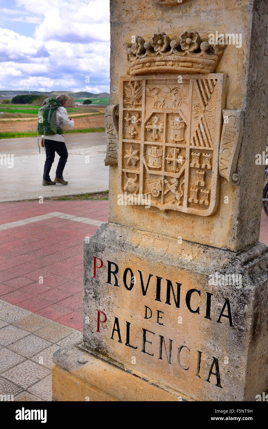 Un pellegrino a piedi il Camino de Santiago de Compostela passa un monumento che segna l'inizio della Provincia de Palencia. Foto Stock