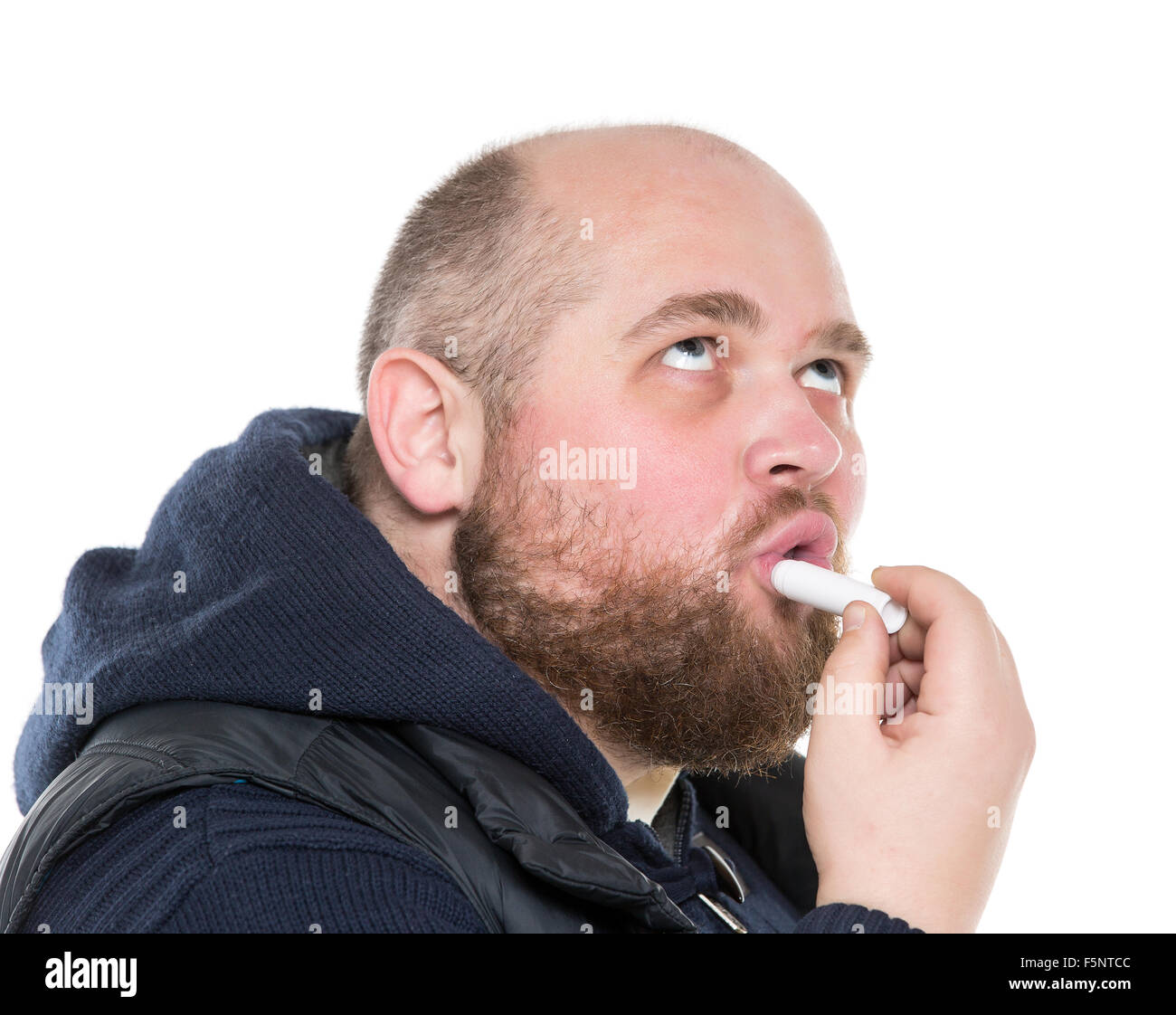 Bald barbuto uomo grasso utilizza un rossetto protettivo, su sfondo bianco Foto Stock