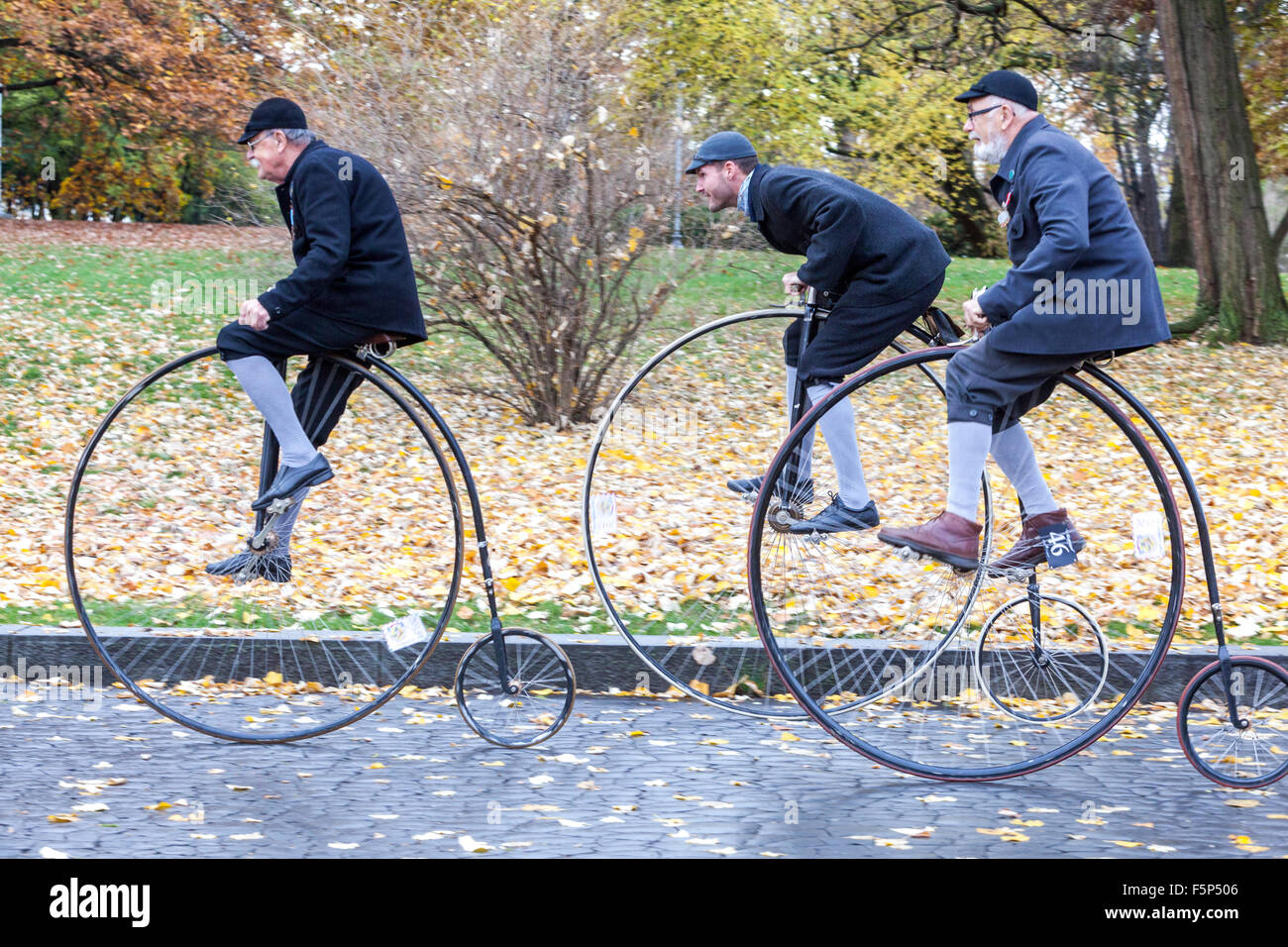 Tre uomini in una tradizionale gara di ciclismo di Penny Farthing. Partecipanti vestiti in costumi d'epoca, Praga Letna Park Autunno Repubblica Ceca invecchiamento attivo Foto Stock