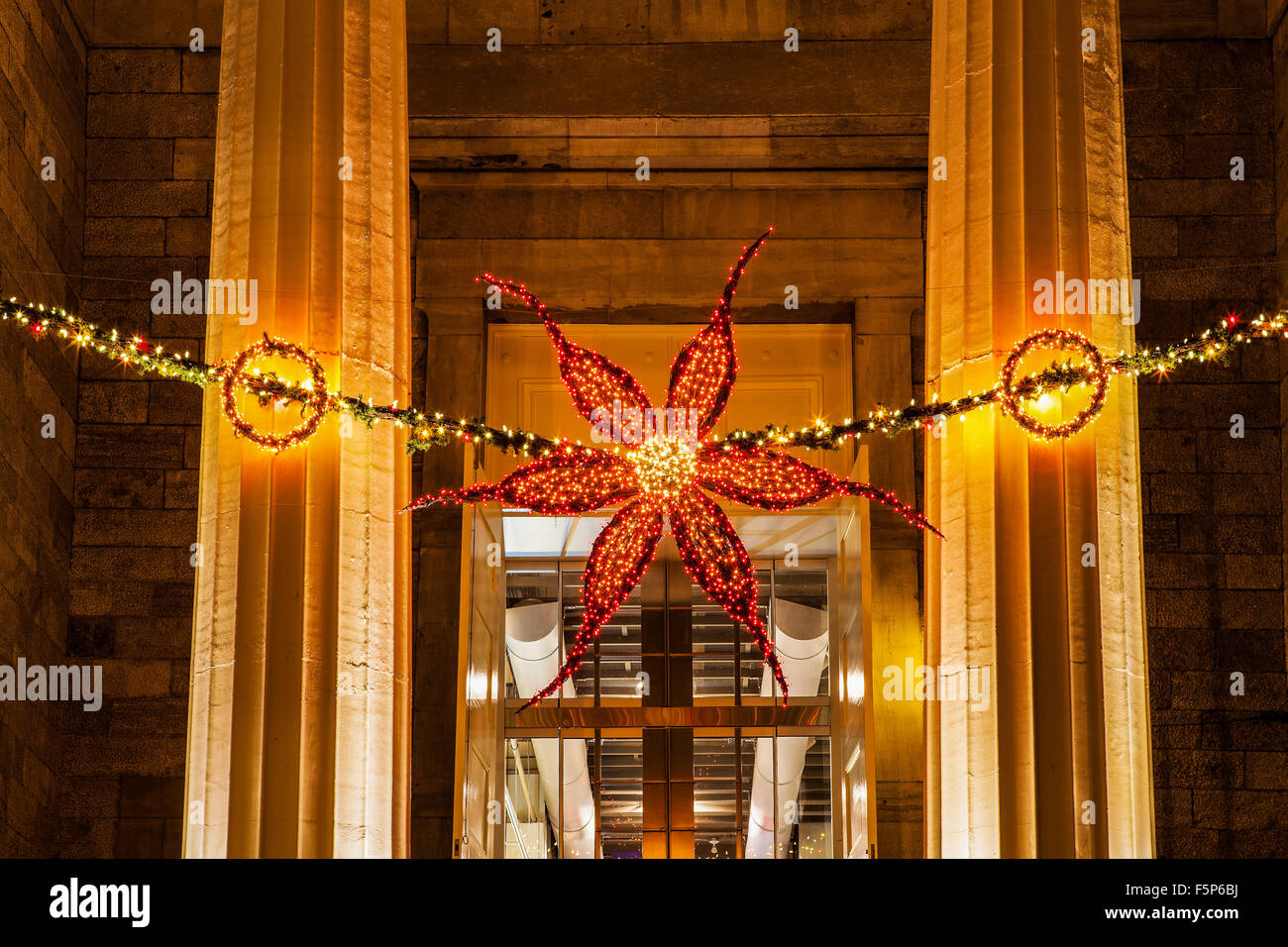 Poinsettia forma la luce di natale decorazione appeso alla porta di un edificio commerciale. Foto Stock