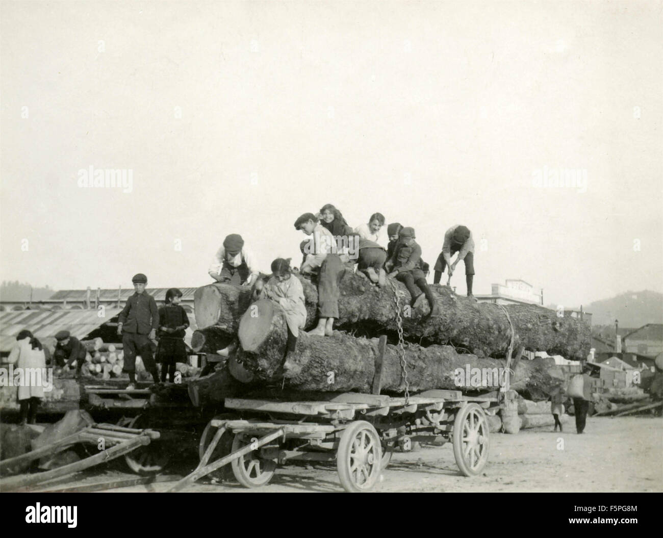 Un folto gruppo di bambini contribuisce a legare i log su un carro, Italia Foto Stock