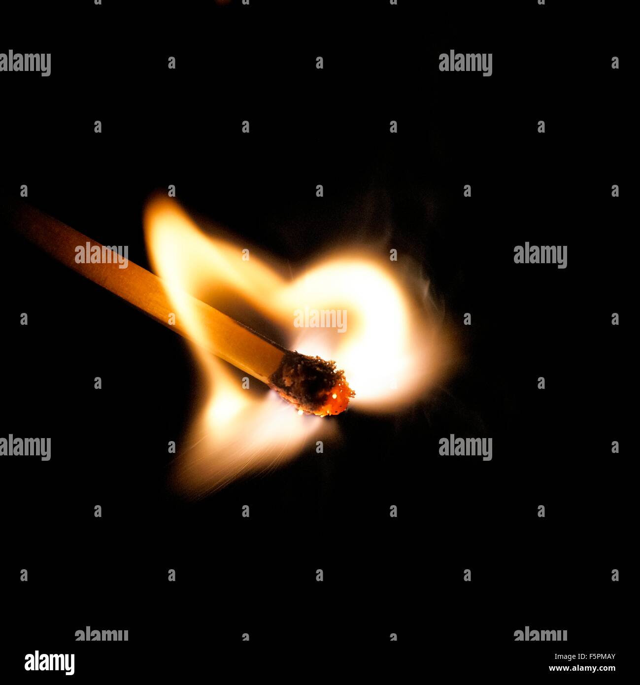 Matchstick sul fuoco contro uno sfondo nero. Foto Stock