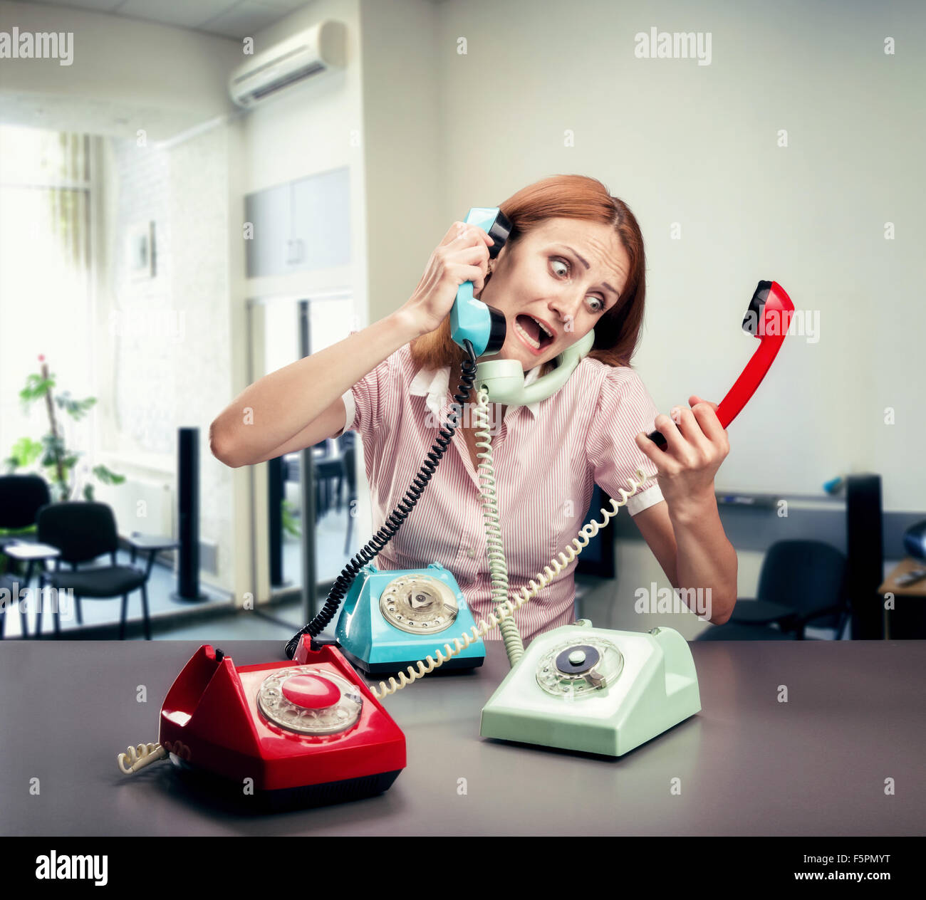 Ha sottolineato la donna con tre telefoni in ufficio Foto stock - Alamy