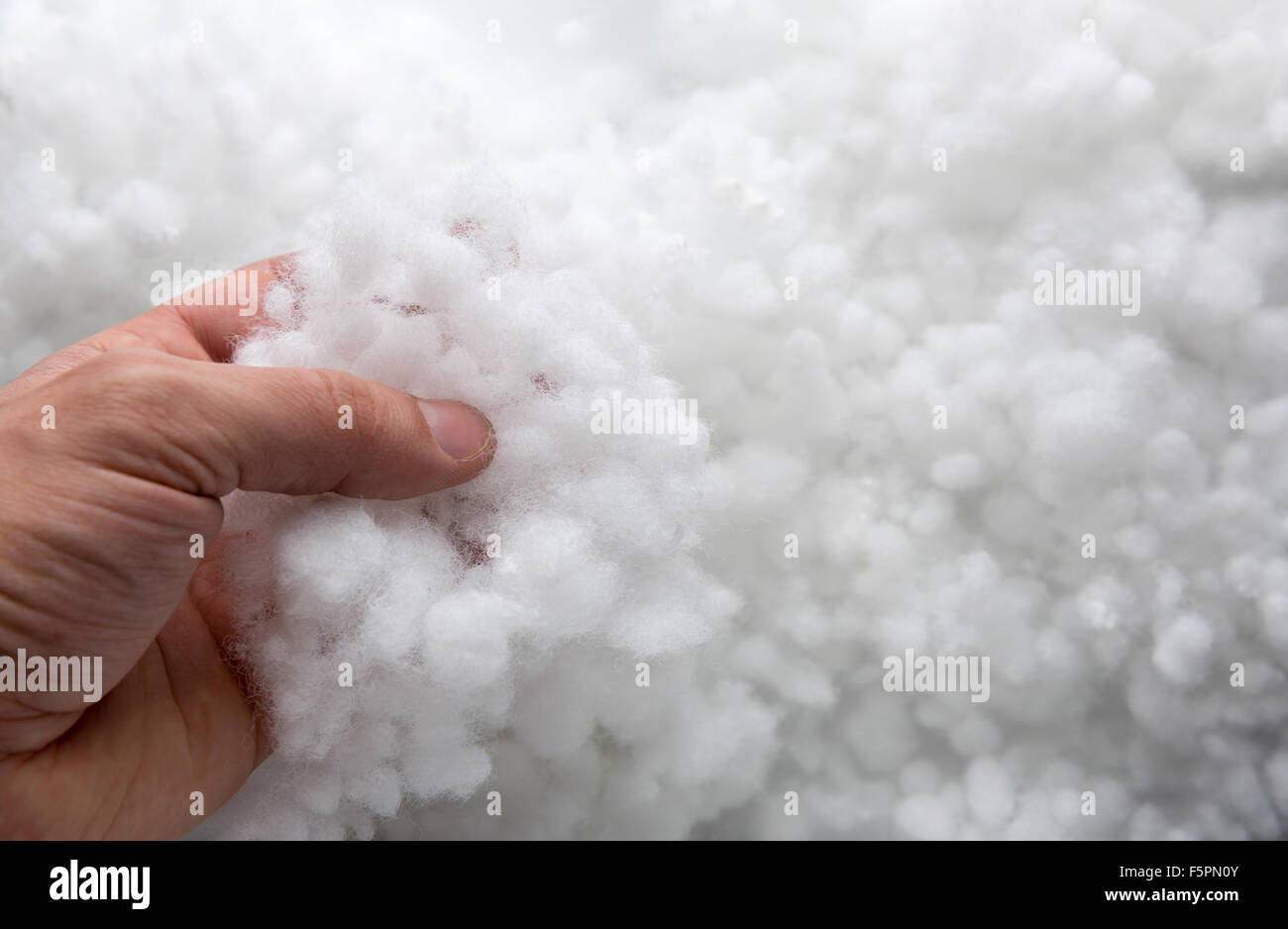 Primo piano di una mano prendendo riempitivo sintetico Foto Stock
